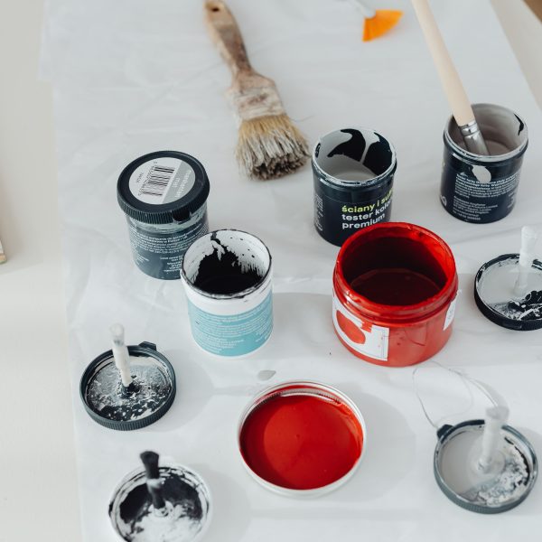 Assorted paint cans and brushes on a white surface, Pexels 6920160.
