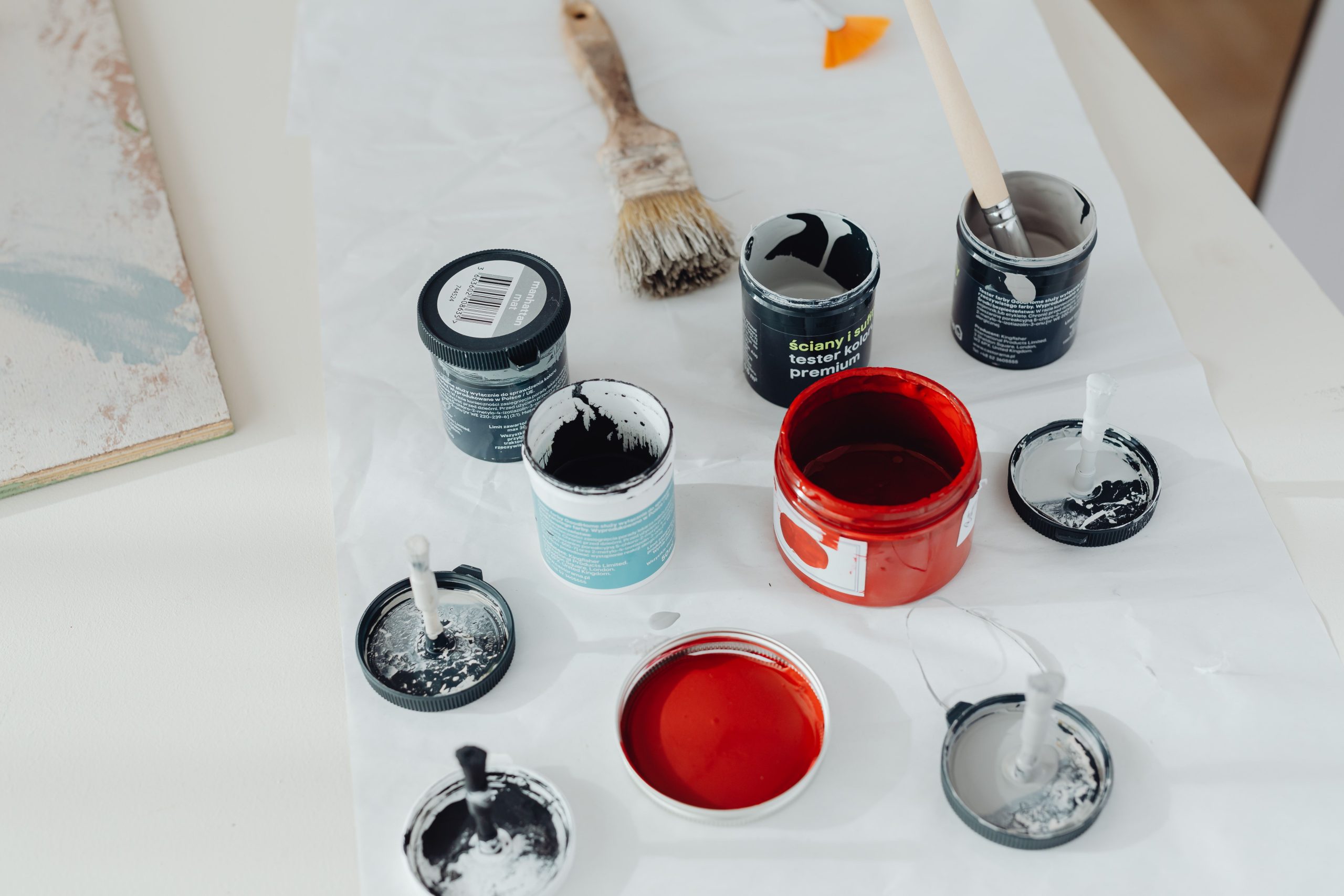 Assorted paint cans and brushes on a white surface, Pexels 6920160.